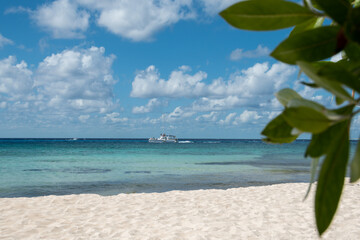 Boat in turquoise ocean water against blue sky with white clouds. Natural landscape for summer vacation.