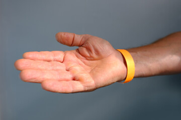 close-up of yellow paper bracelet, check tape with entry number on hand of middle-aged european...