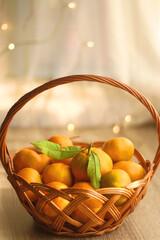 Vintage basket filled with fresh tangerines. Bokeh lights in the background. Selective focus.