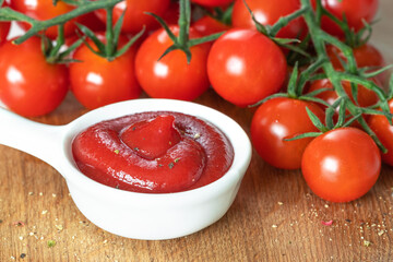 ketchup in a white sauce pan, cherry tomatoes on a branch close-up