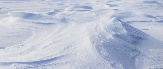 Snowy background, snow-covered surface of the earth after a blizzard in the morning in the sunlight with distinct layers of snow