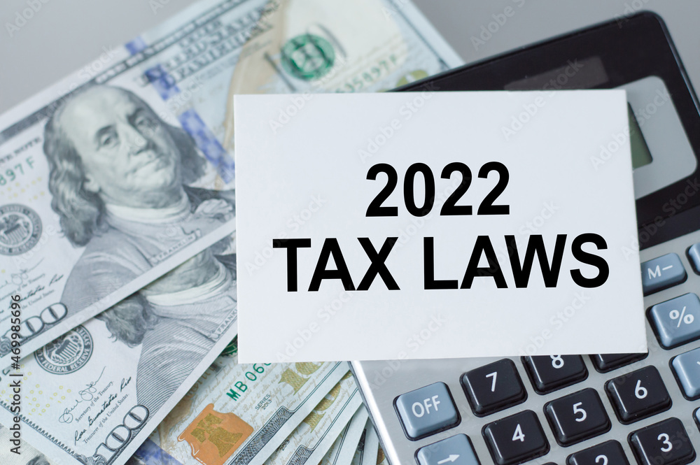 Poster card with a message 2022 tax laws on the background of a calculator next to dollars on the table