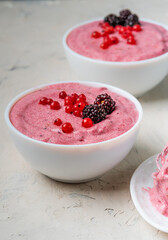 A healthy pudding of semolina and currant with blackberries served in a white bowl.