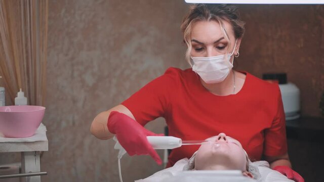 A beautician makes a darsonvalization of the face of a young girl with problem skin.