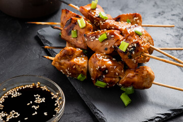 Chicken fillet yakitori close-up on a dark background and served on a slate dish. Close-up, selective focus.