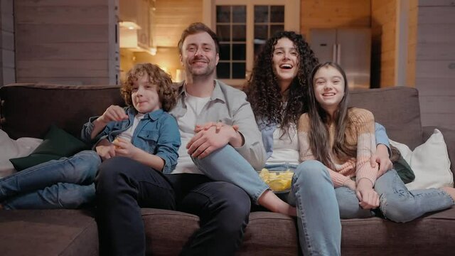 Family watching a movie together at home hugging and laughing with comedy. Family spends time together in lockdown. 50fps. High quality 4k footage