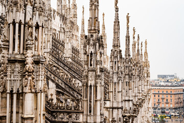 Fototapeta na wymiar High spires with sculptures on top in the Duomo. Milan, Italy