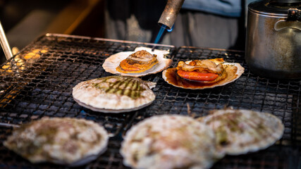Merchant sale scallop in Tsukiji fish market. Man preparing seafood at shops