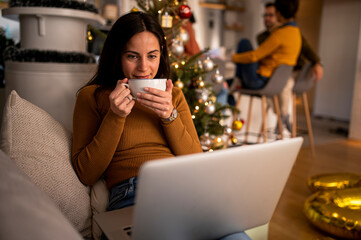 Photo of cute nice charming, attractive girl working in eve of new year with her laptop and drinkig coffee
