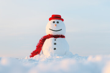 Funny snowman in stylish red hat and red scalf on snowy field during sunset. Merry Christmass and happy New Year