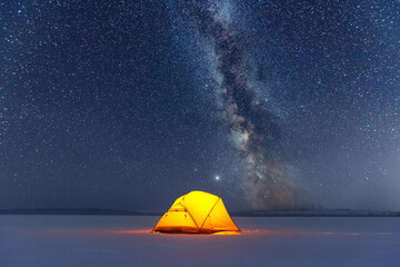 Yellow tent lighted from the inside against the backdrop of incredible starry sky with Milky way. Amazing night landscape. Tourists camp in winter mountains. Travel concept - Powered by Adobe