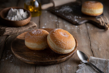 Fresh donuts sprinkled with sugar crumbs on a wooden table
