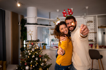 Young cheerful couple having fun with sparklers on New Year's eve at home.
