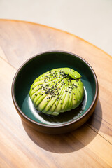 entire avocado sliced into thin pieces together covered in sesame seed