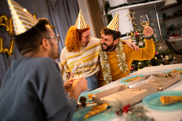 Three friends enjoying at the new year's party in their apartment laughing and drinking champagne.