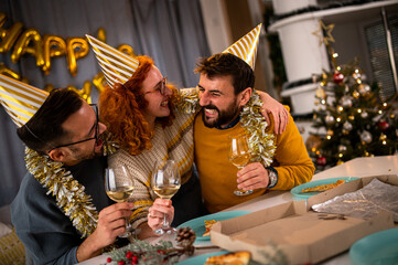 Three friends enjoying at the new year's party in their apartment laughing and drinking champagne.