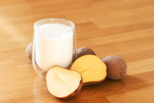 Potato milk photo on wooden background. Glass of alternative milk. Plant based vegetarian beverage. Lactose free drink