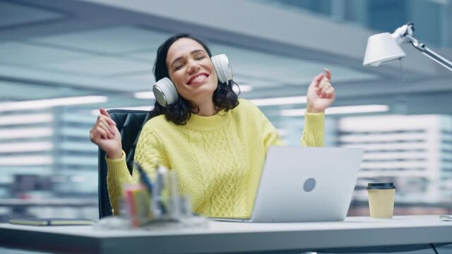 360 Degree Office: Smiling Hispanic Businesswoman Sitting at Desk Working on Computer, Wearing Headphones, Listening Music, Dances. She's Happy, Enjoys Herself, having Fun. Moving Around Tracking Shot