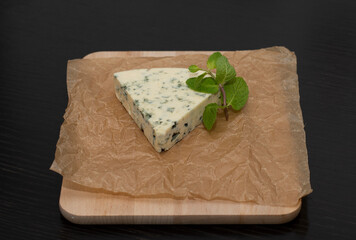 Slice of Blue cheese with mold on a paper background with mint decoration