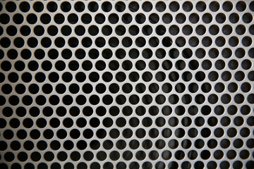Macro shot of speaker grille. Vintage effect. Close up shot of a round speaker. Acoustic broadband speaker. Luxury car stereo system speaker. Holes in a metal lattice.