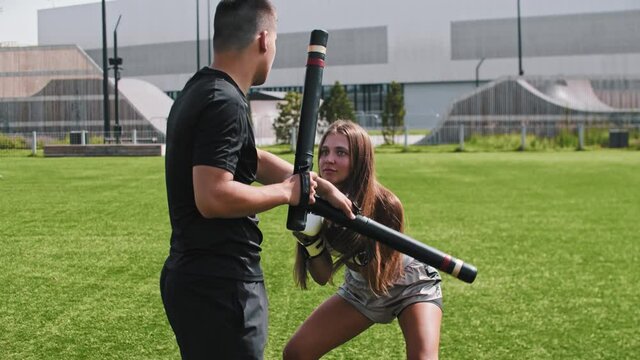 Young woman in shorts dodging on karate training with her male coach 