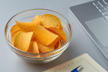 eating potato chips working laptop notebook grey table unhealthy snack
