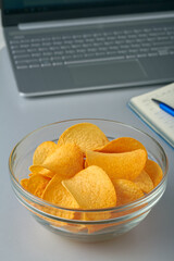 eating potato chips working laptop notebook grey table unhealthy snack
