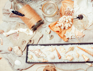 a lot of sea theme in mess like shells, candles, perfume, girl stuff on linen, pretty textured post card view vintage close up