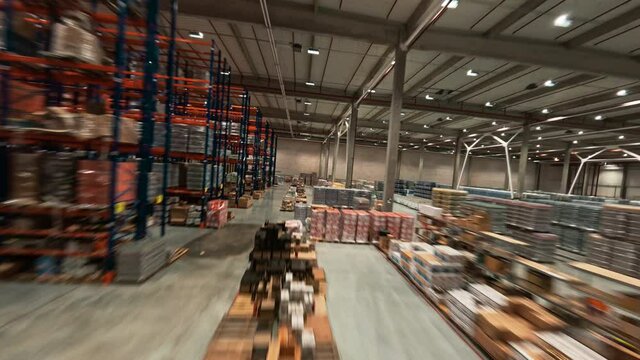 Maneuverable FPV copter flight in the logistic park. Rows of delivery goods on shelves, cardboard boxes and packages. Retail warehouse. Storehouse.