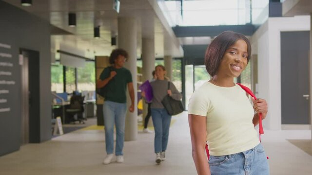 Portrait of smiling female student in busy university or college building - shot in slow motion 