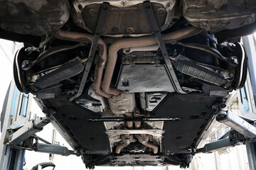 The car service has a modern car on a lift. Bottom view of the car. Selected focus.        