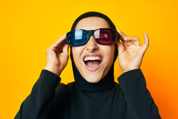 cheerful woman in black hijab popcorn 3D glasses cinema yellow background