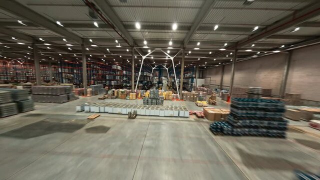 Speed flight in modern warehouse. Huge industrial building filled with delivery goods. Logistic park product distribution center. Aerial FPV view.