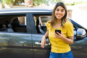 Attractive woman texting next to her car
