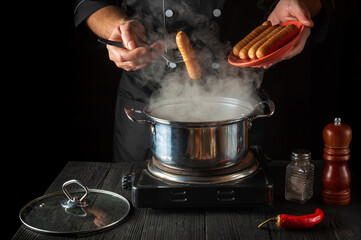 The cook cooks Vienna sausage in a saucepan. Working environment in the restaurant kitchen....