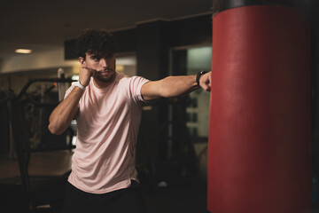 a young man hitting a punching bag in a gym.