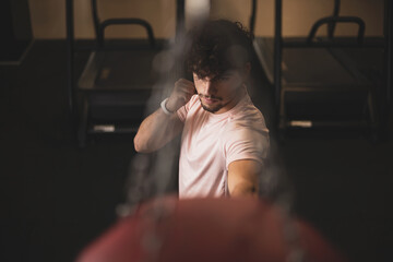 a young man hitting a punching bag in a gym.