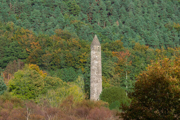 Glendalough Round tower with autumn forest background.