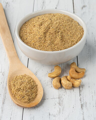 Cashew nut flour in a bowl and in a spoon over wooden table. Gluten free flour