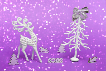 Merry Christmas and Happy New Year. Festive poster with a Christmas tree, a deer, a sleigh on a purple background with lights. New year 2022 copy space close up