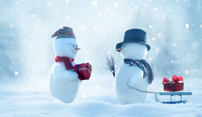 Two  cheerful snowman  standing in winter christmas landscape. Winter fairytale.Snowfall in the magic forest.Merry christmas and happy new year greeting card.