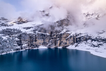 Fototapeta na wymiar Oeschinensee Lake in Switzerland Surrounded by Snow Covered Trees and Mountains