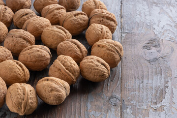 A scattering of beautiful ripe walnuts in unopened shells on a vintage wooden background.