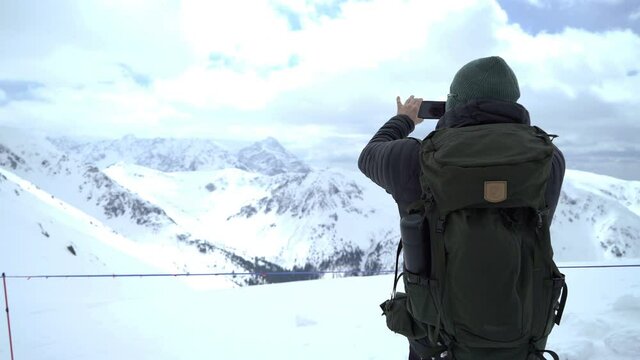 Man uses a smartphone to video a beautiful view in the mountains