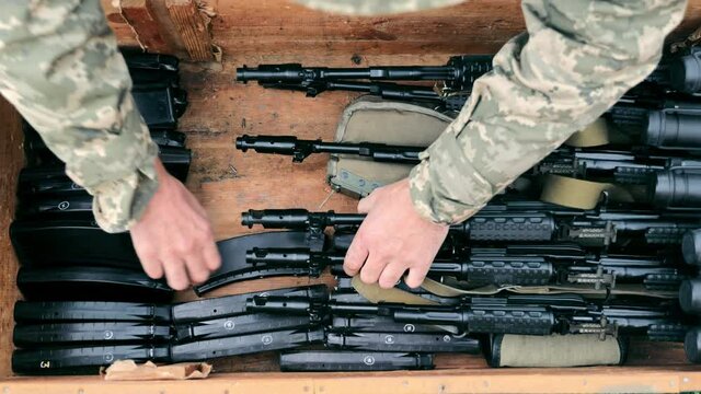The military puts ammunition in a box. Sorting ammunition and submachine guns in a wooden box. Military ammunition.