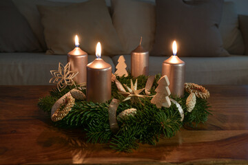 Third Advent with three lit golden candles on an Advent wreath with natural Christmas decoration on...