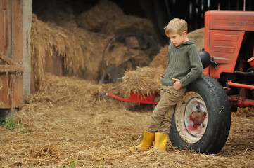 Little boy in the countryside next to the tractor