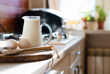 Fresh milk and eggs on wooden board in real home kitchen interior with natural light