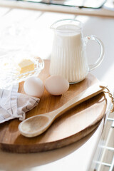 Fototapeta na wymiar Fresh milk and eggs on wooden board in real home kitchen interior with natural light
