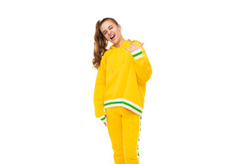 Photo of a beautiful smiling girl with dark hair with a ponytail in a stylish yellow tracksuit with green stripes shows rock hand isolated on white background with free space for text